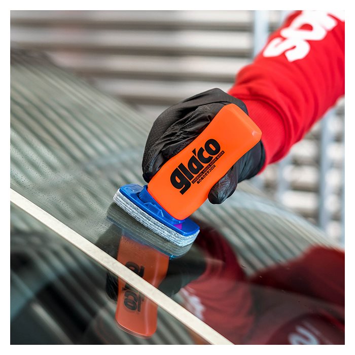 Hand met Glaco DX glasbeschermer op autoruit nabij wit tape