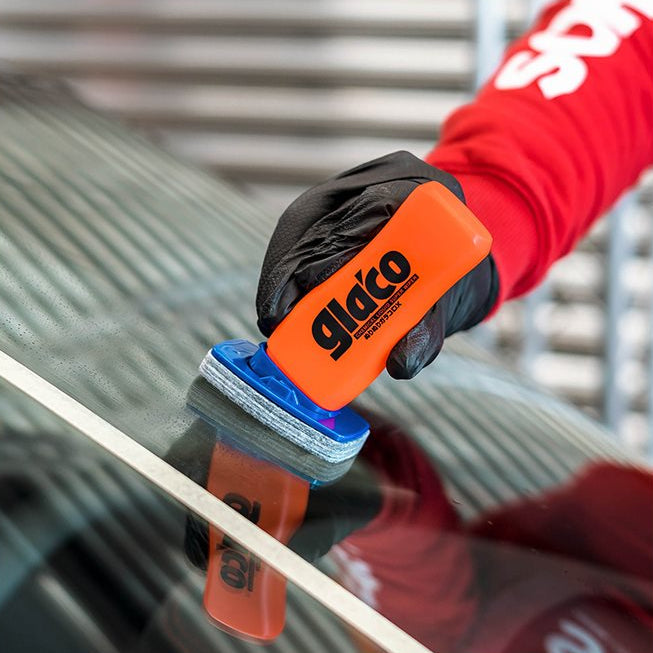 Hand met Glaco DX glasbeschermer op autoruit nabij wit tape