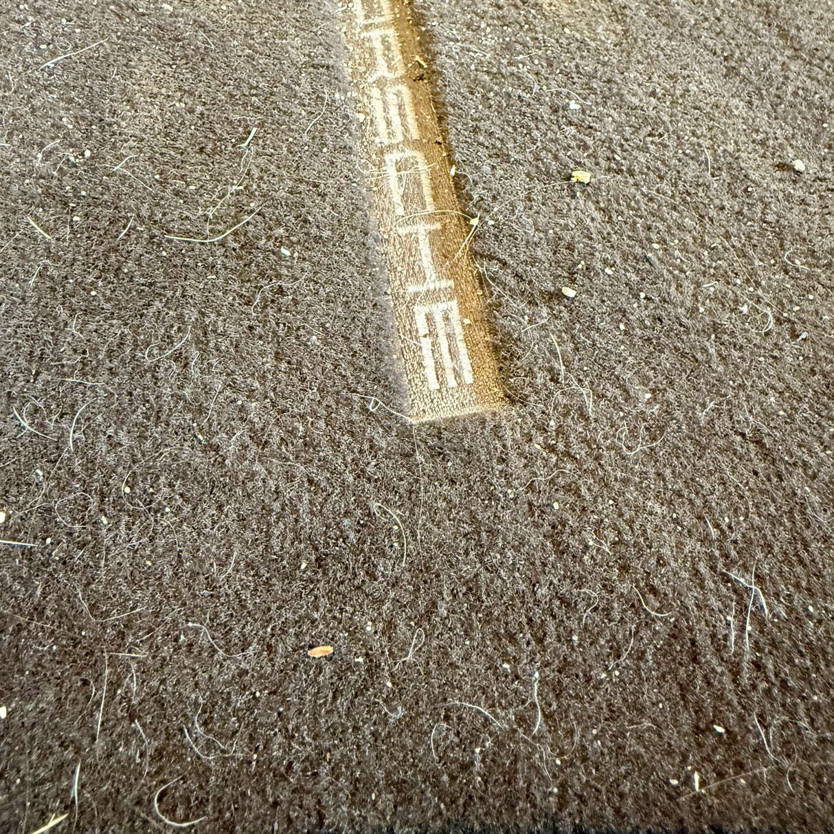 Voorafbeelding van een zeer vuile automatten met Porsche-logo vóór TurboClean stofzuiger