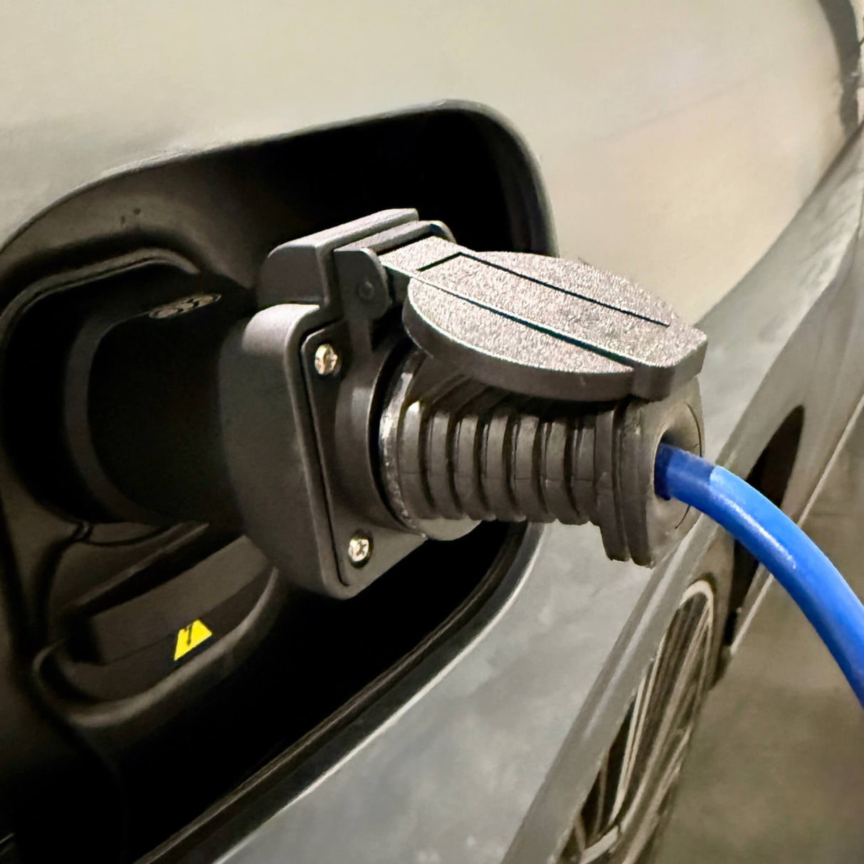 Hand die de GCG Max V2L-adapter in de laadpoort van de auto plaatst of verwijdert