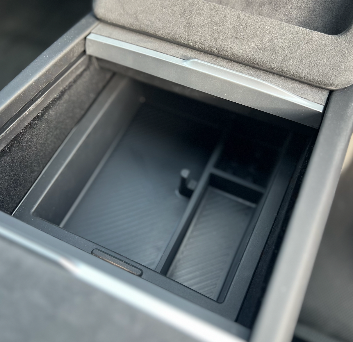Doos voor middenconsole in een auto, geopend en leeg weergegeven.