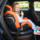 Pige vinker og sidder i Recaro Xenon 1 Kid autostol, set gennem åben bildør