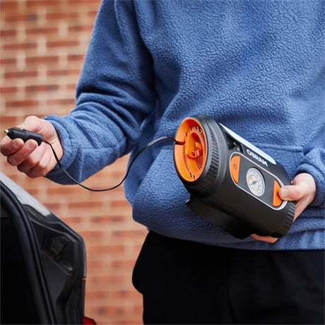 Person holder Osram TYREinflate 2110 kompressor med ledning, klar til brug ved bil