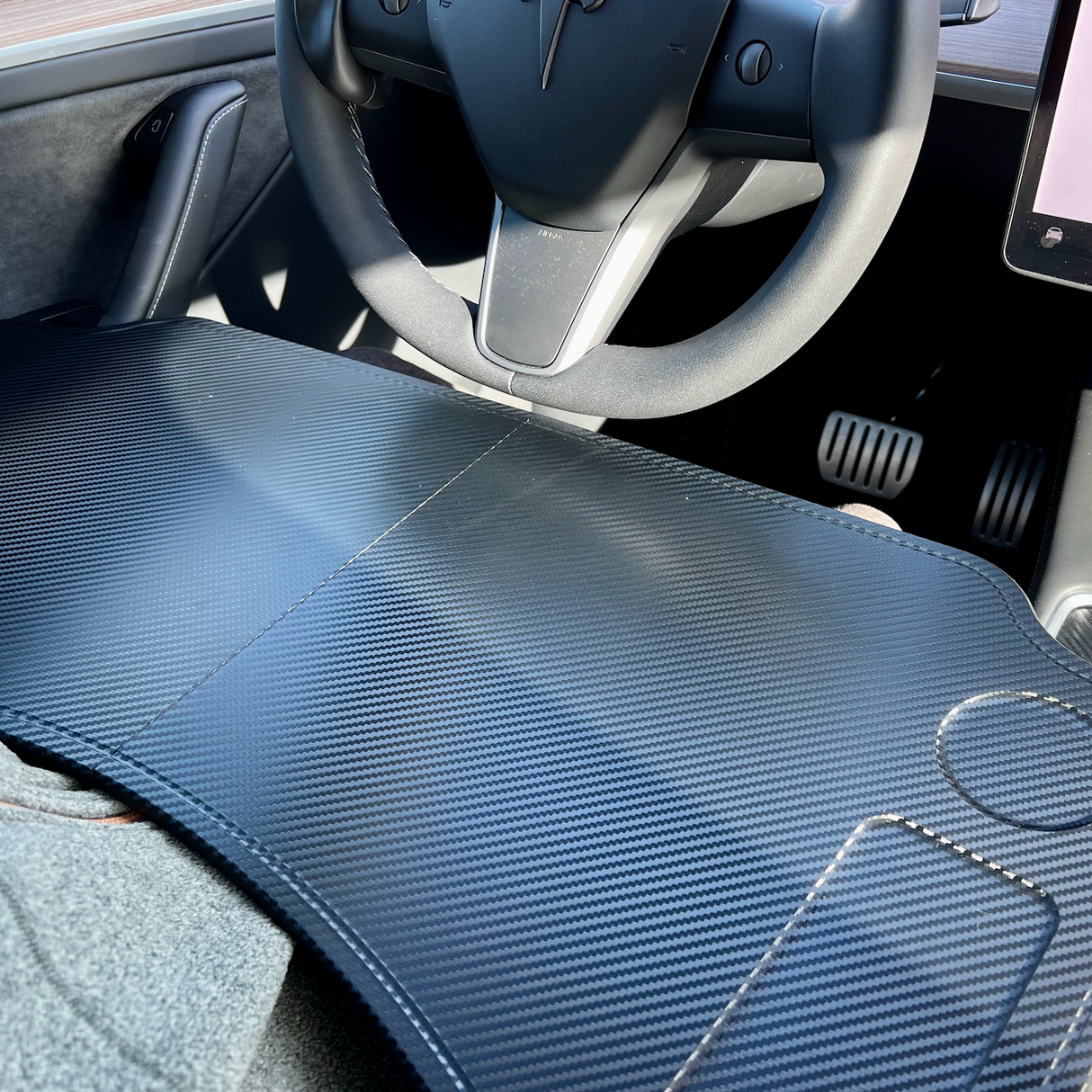 Opvouwbare tafel in donker carbon-look, gezien binnenin een Tesla-auto