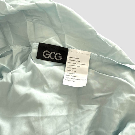Lichtblauw GCG MAX bamboe hoeslaken met labels die wasinstructies en productinformatie tonen.