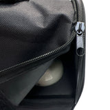 Zwarte tas met open ritssluiting en een reflecterende bal erin