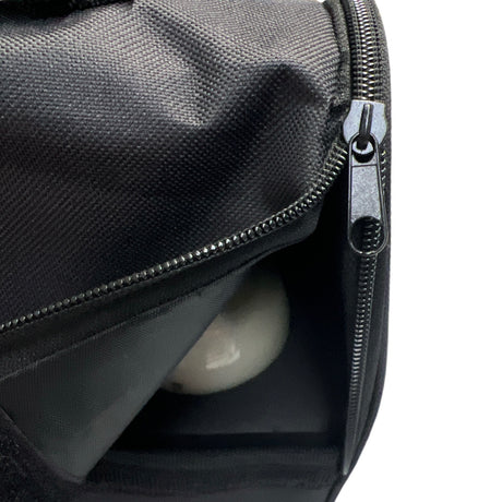 Zwarte tas met open ritssluiting en een reflecterende bal erin