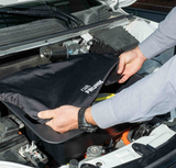Handen die een beschermhoes over de frunk-opbergdoos in de auto leggen