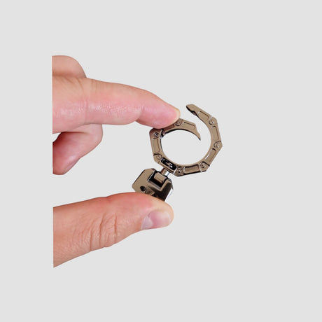 Persoon houdt een sleutelcover/ring voor Toyota bZ4X tussen twee vingers tegen een neutrale achtergrond.