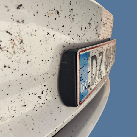 Vuil witte auto met insectenresten en kentekenplaat