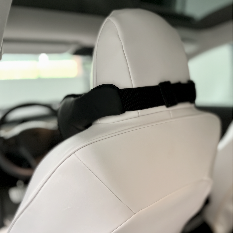 Neksteun bevestigd aan de witte autostoel voor extra comfort tijdens de rit.