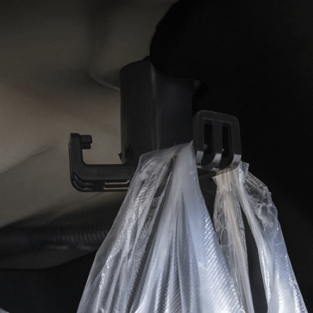 Een tashaak gemonteerd in een Tesla Model 3. Er hangt een doorzichtige tas aan de haak.