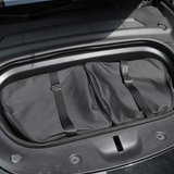 Tasset met twee zwarte opbergtassen in de frunk van een Tesla Model Y.